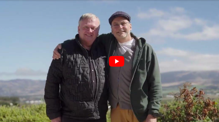 Two men embracing and smiling to camera