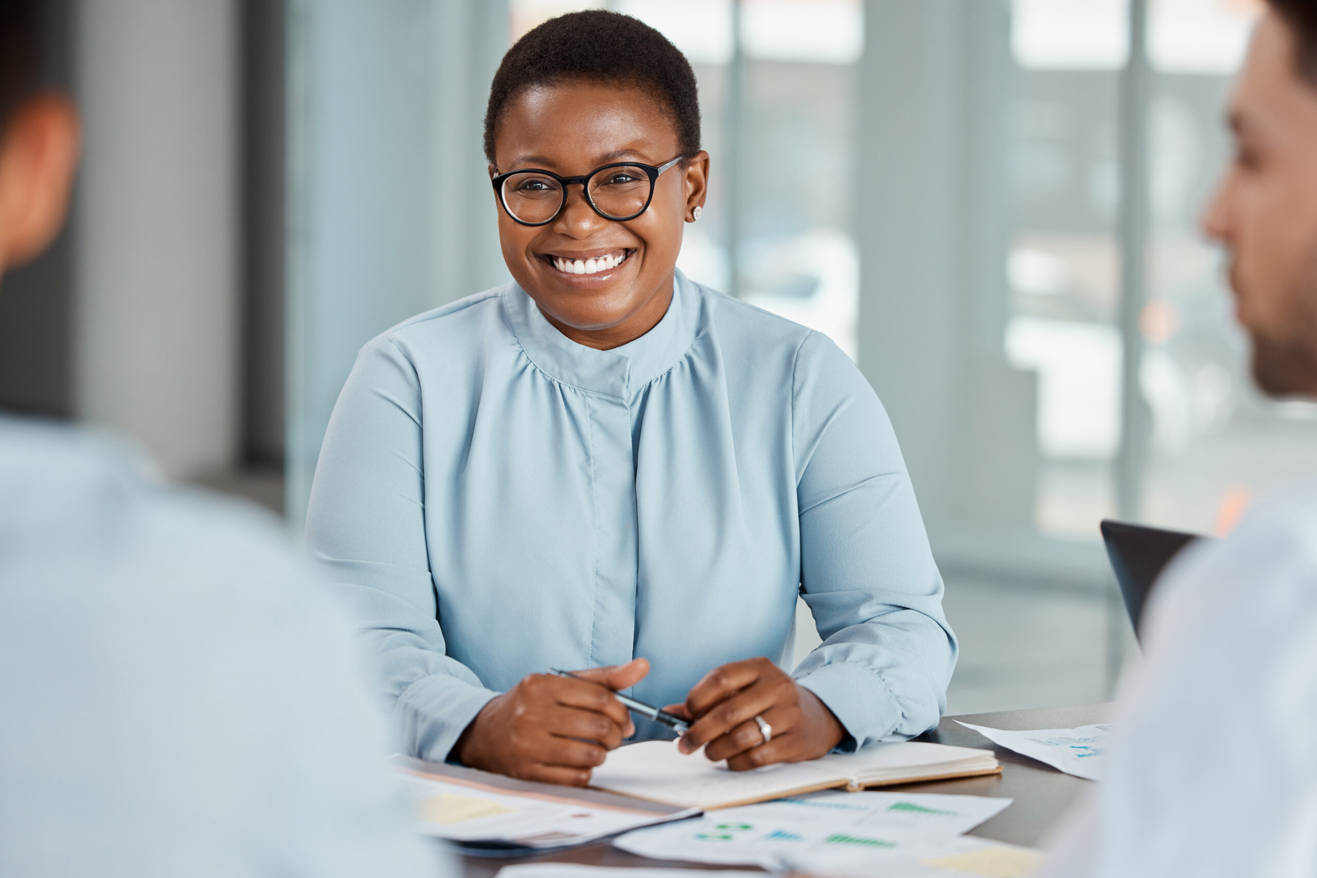 A woman with glasses smiling at her colleague during a meeting