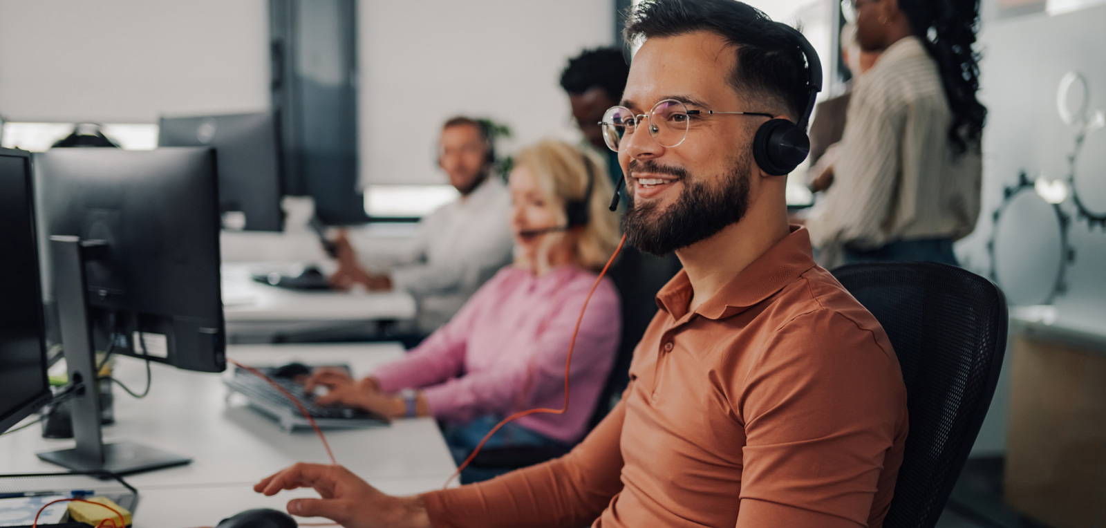 People working at a call center - sitting at desk with headphones