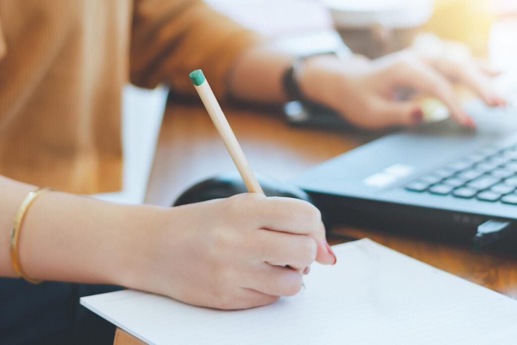 A person writing in a notebook while working