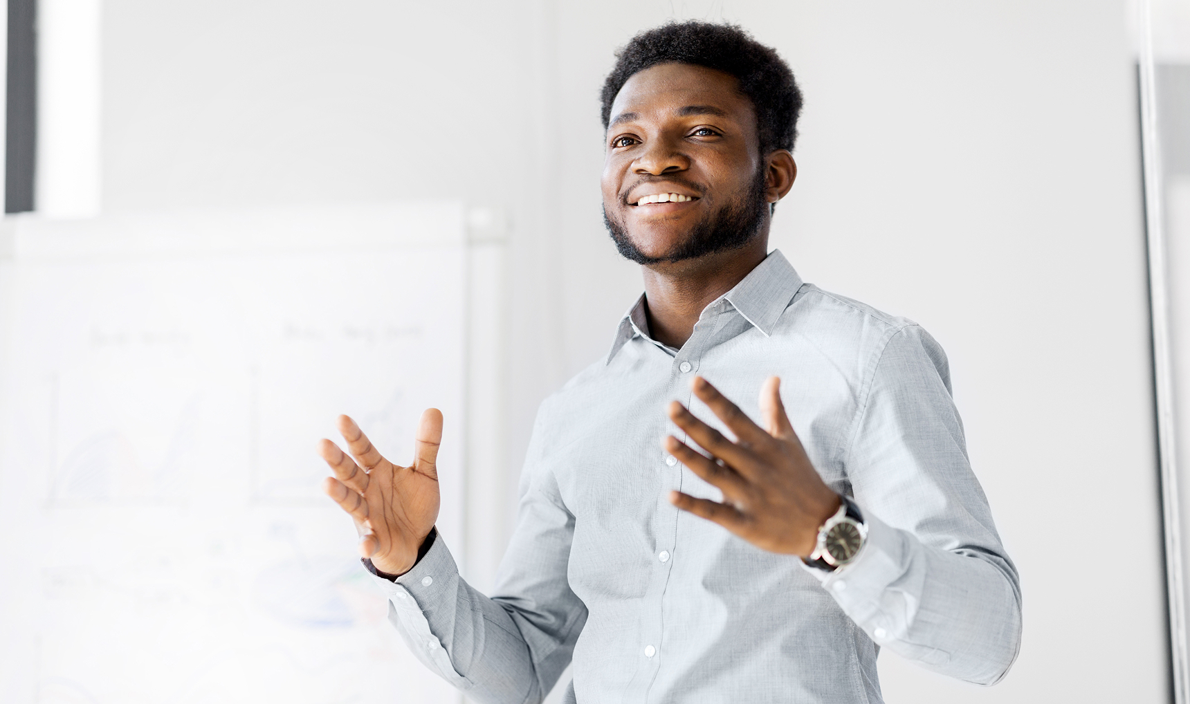 A man speaking to a group, gesturing with his hands and smiling to the room